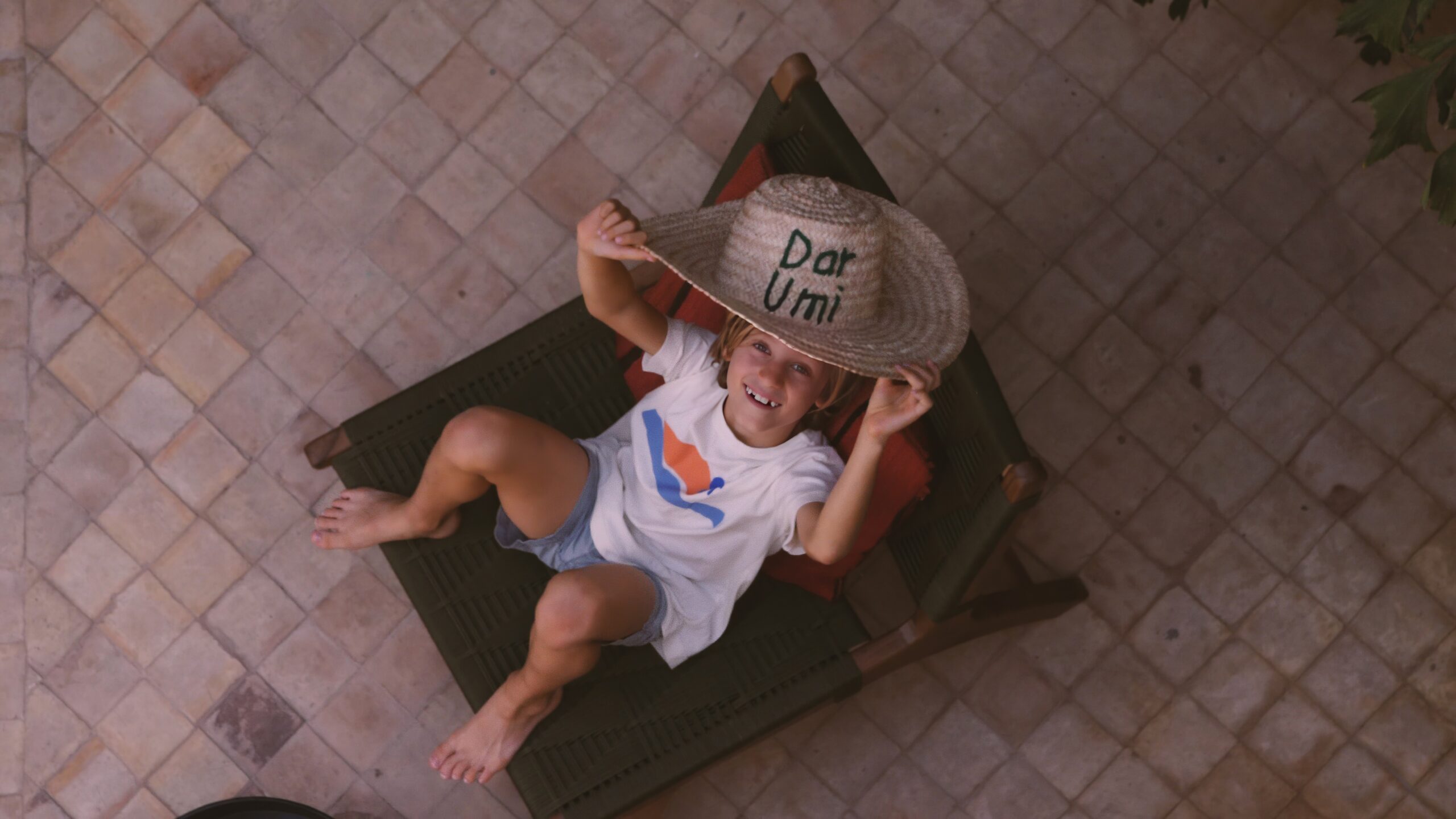 a child sitting on a chair with a hat on