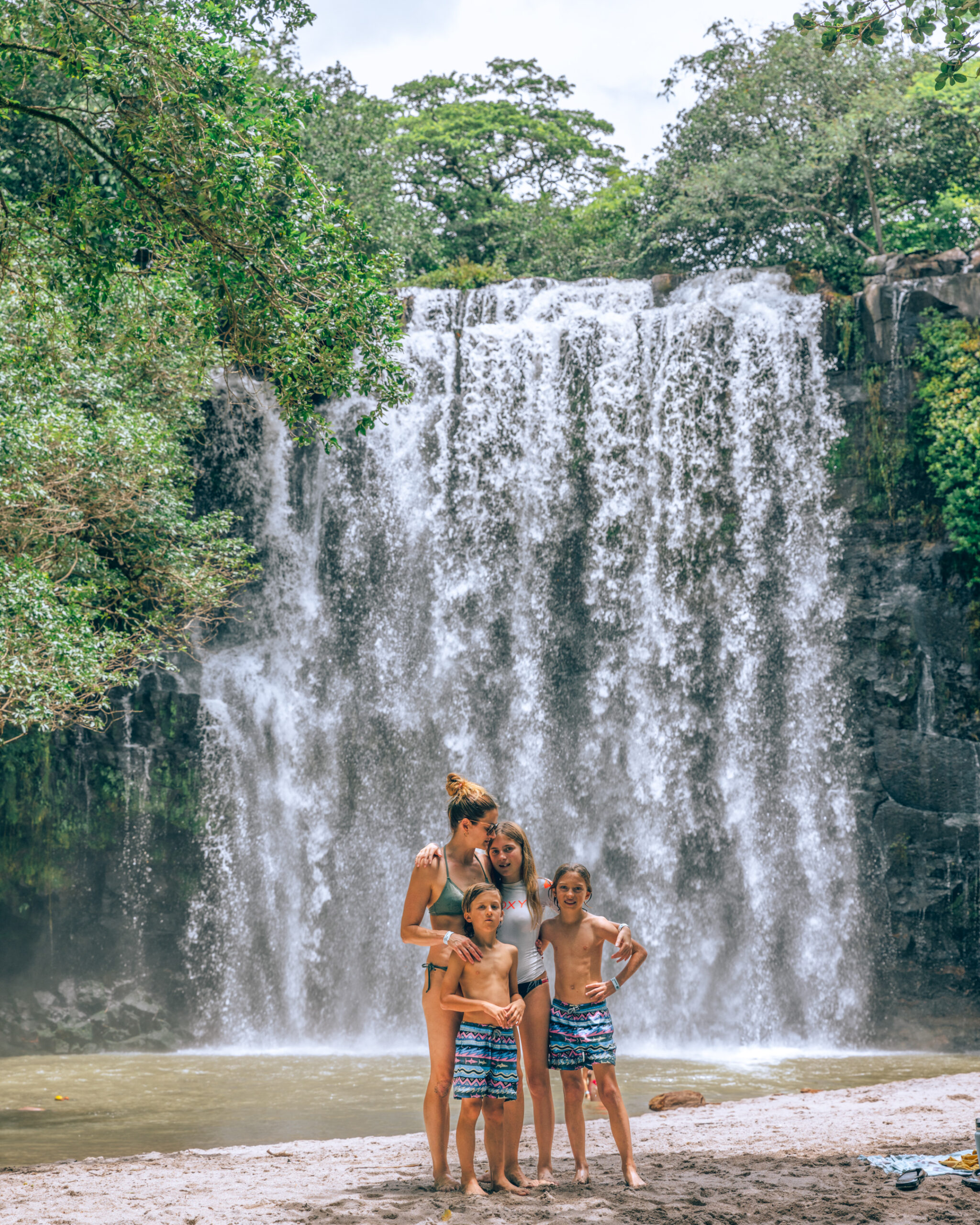 Family posing by large waterfall.