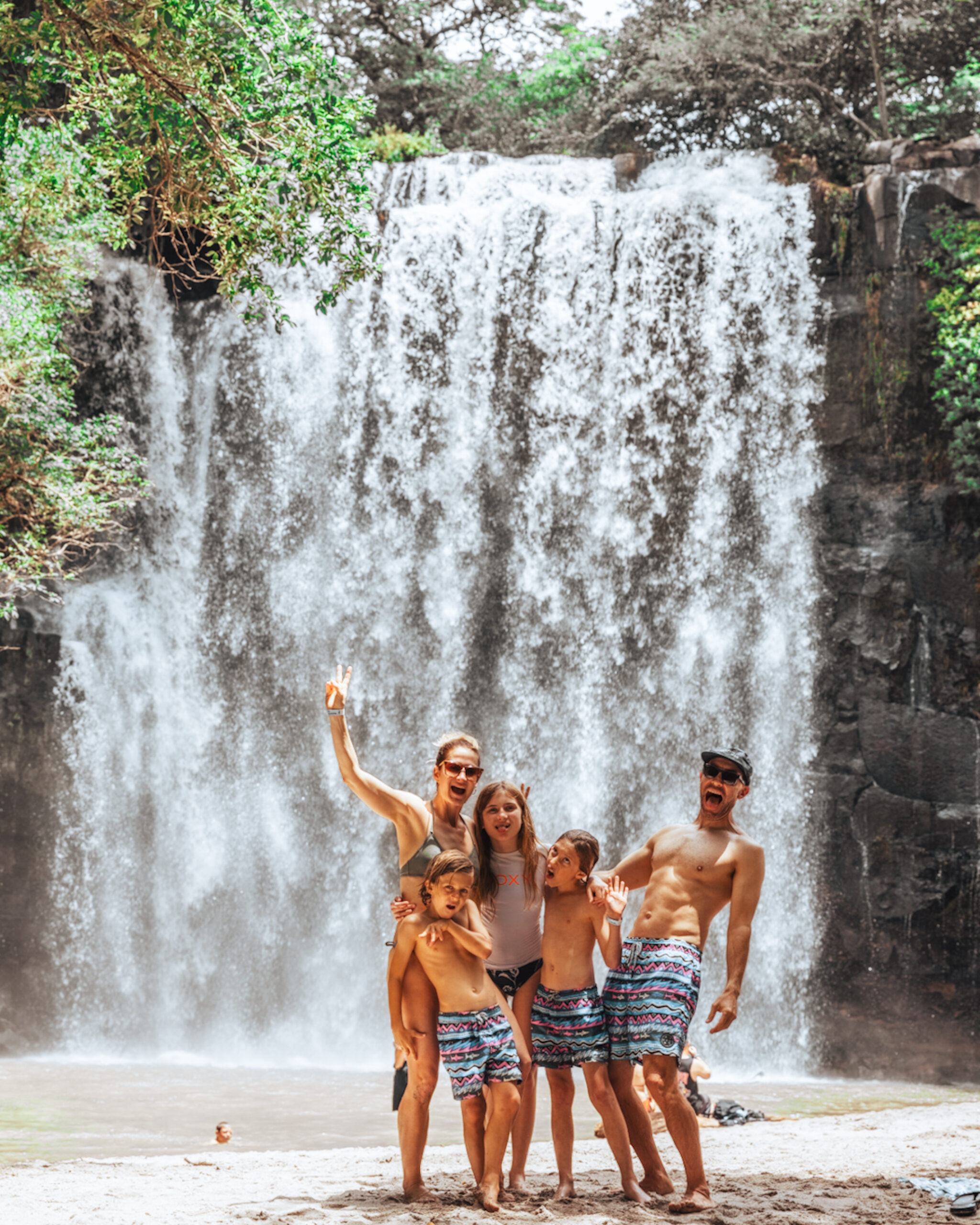 Family posing by large waterfall.