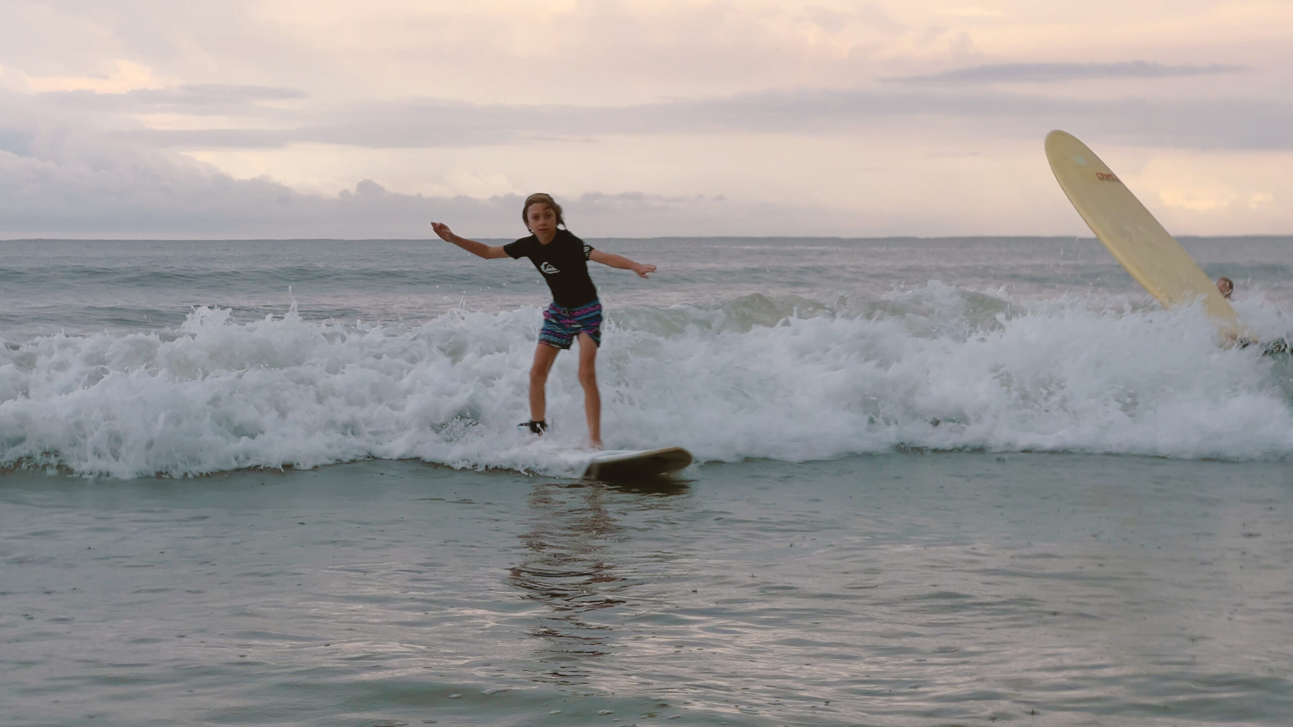 Child surfing in ocean waves.